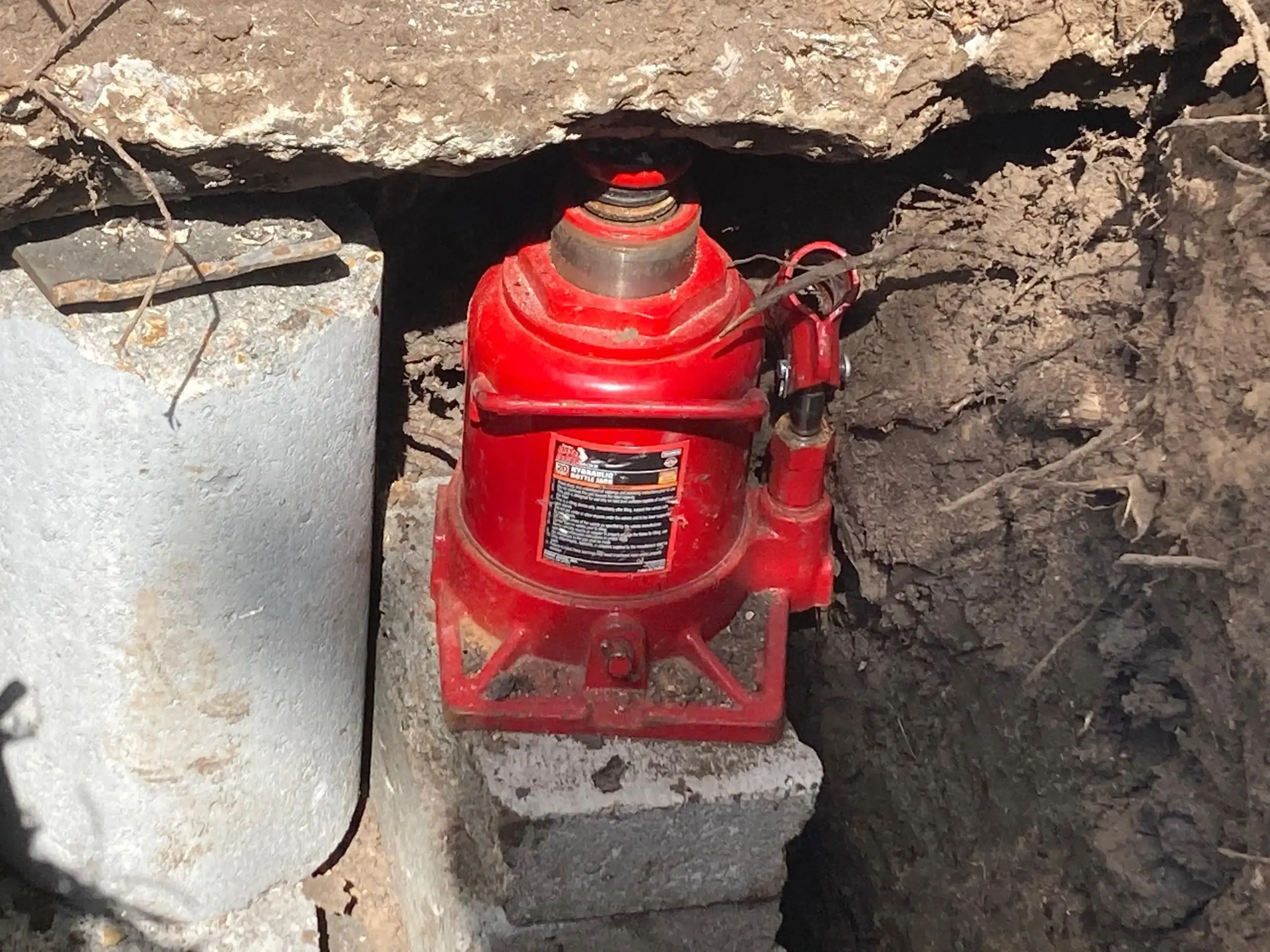 Houston foundation repair — hydraulic jack lifting a foundation pier by FNF Foundation Repair